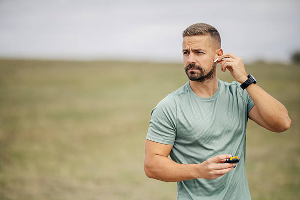 istock Man putting wireless earbud into ear outdoors 2243919752