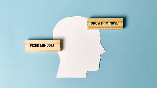 istock Growth Mindset versus Fixed Mindset concept with wooden blocks positioned on a human head silhouette, representing psychological and business development concepts. 2243922548