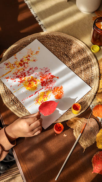 istock Autumn leaf art project with a child's hand holding a red leaf. 2243923266