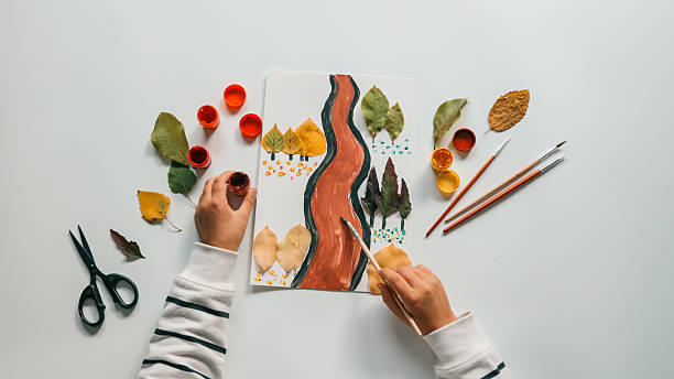 istock Child's artwork with autumn leaves and paint 2243923274