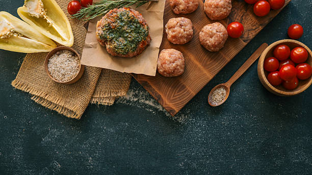 An overhead shot features various ingredients like meatballs, tomatoes, and herbs, arranged on a wooden board and rustic surface.