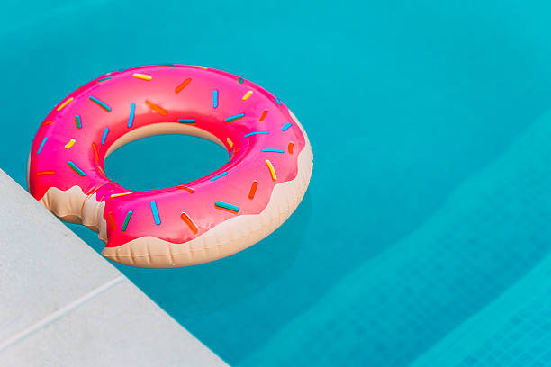 istock Donut-shaped inflatable ring floating in a bright blue swimming pool 2243924847