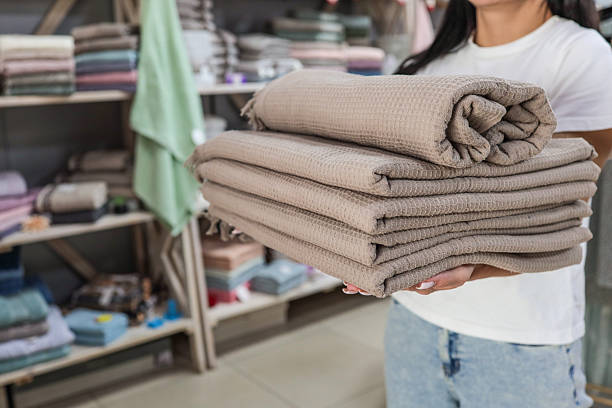 istock Woman holding a stack of folded waffle weave blankets in a store. 2243925334