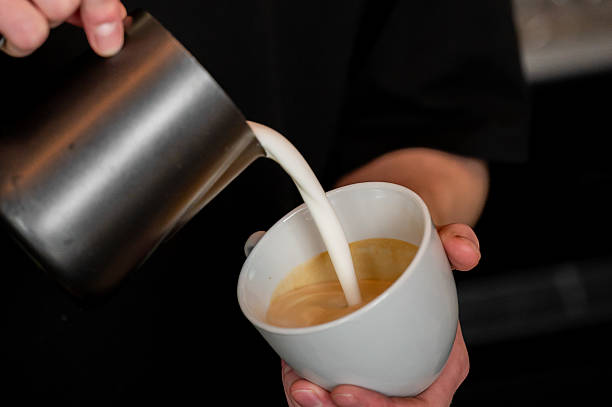 istock A barista pours steamed milk from a metal pitcher into a white ceramic cup to create latte art, with the warm coffee mixture visible inside the cup. The focus is on the pouring technique 2243928263