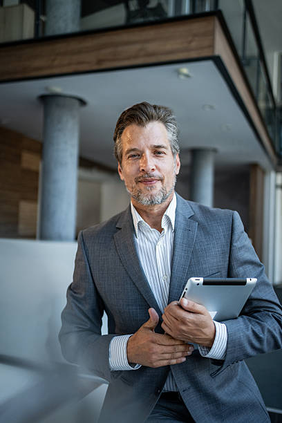 istock Mature businessman holding tablet standing in modern office 2243928864