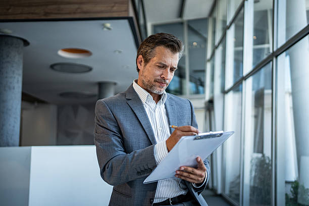 istock Mature businessman writing on clipboard in office 2243928987