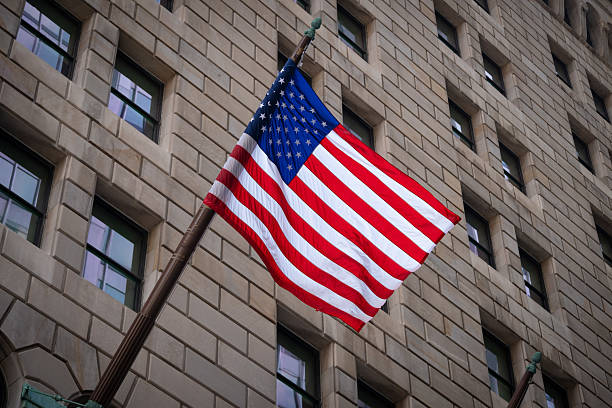 A vibrant American flag waves in front of a stone urban building, symbolizing national pride and heritage in a classic city setting.