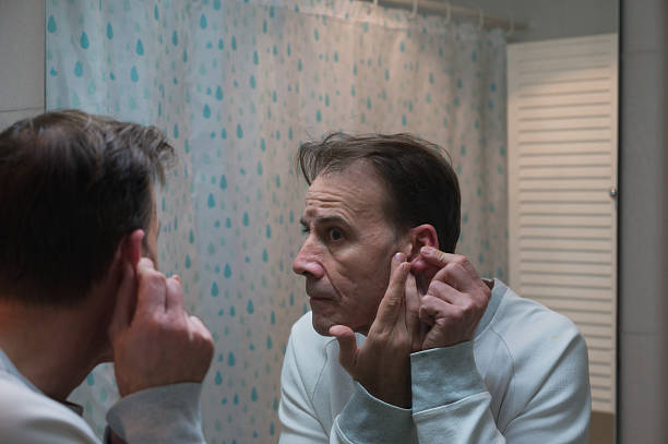 istock A mature man checking his ear at the mirror 2243933720
