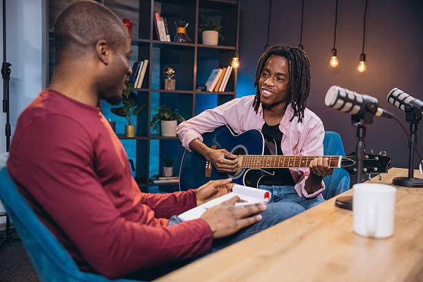 istock African American musician performing guitar, engaging in podcast interview conversation 2243935059