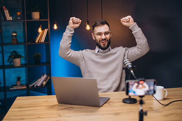 istock Successful podcaster cheering, arms raised during live recording session 2243935418