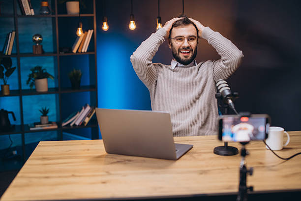 istock Happy podcaster streaming online from a modern home studio, using a smartphone and microphone to create engaging content 2243935423