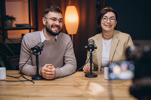 istock Two podcasters smiling and engaging while recording an exciting new episode in a modern studio filled with professional equipment 2243935480