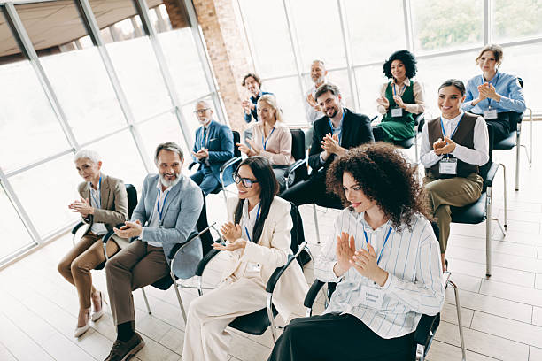 istock Business professionals applauding during a seminar in a bright office setting, showcasing teamwork, collaboration, and diversity in a corporate workspace. 2243935546