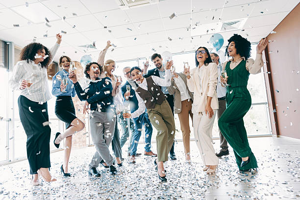 istock Large team joyfully celebrating together in a modern office space, enjoying success with confetti and mutual excitement. 2243935851