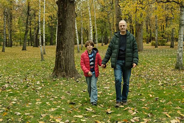 Boy with father walking in the park in autumn, leisure time activity, father and son, healthy lifestyle, love, connection