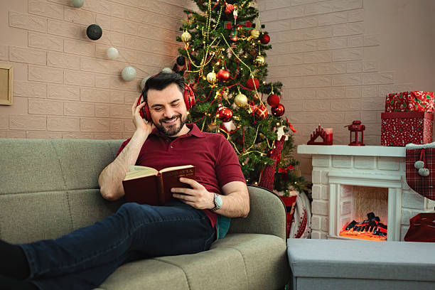 istock Man relaxing on sofa reading book during Christmas holiday 2243939477