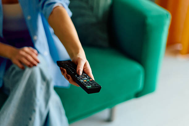 istock Woman holding remote control changing television channels at home 2243945590