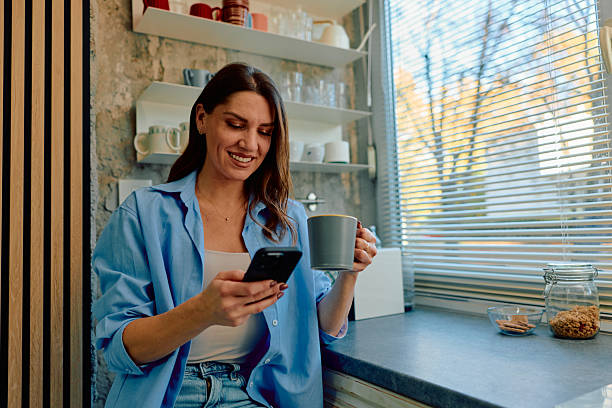 istock Woman enjoying morning coffee and browsing smartphone in kitchen 2243945666