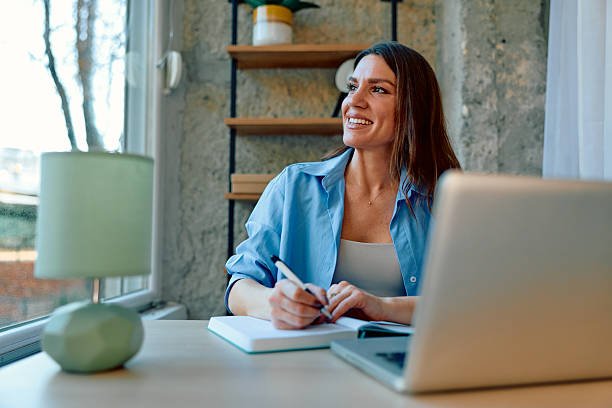 istock Woman working from home writing in notebook smiling 2243945732