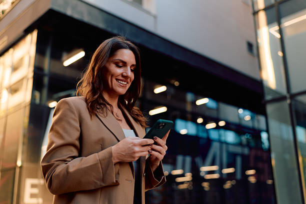 istock Businesswoman smiling while using smartphone in city 2243945786