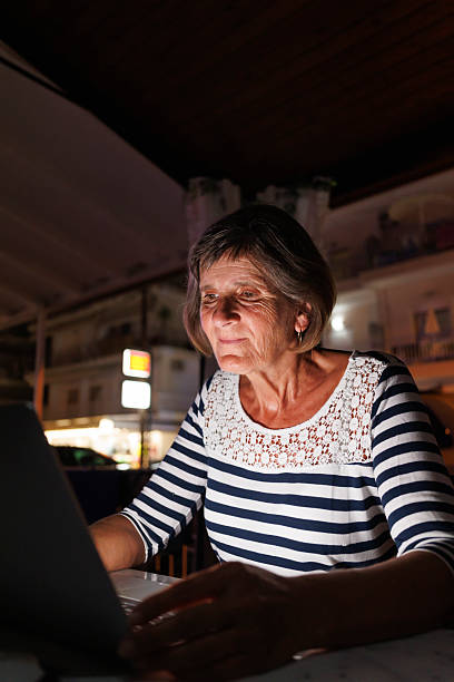 istock Senior Caucasian woman doing online shopping using laptop computer at home at night 2243947377