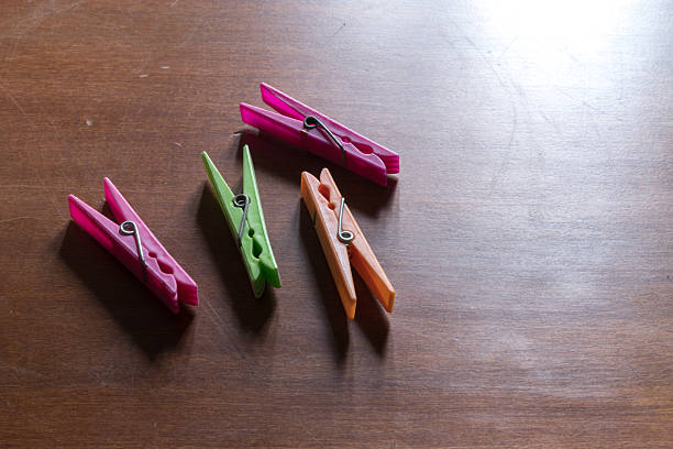 Four colorful plastic clothespins are scattered casually on a dark wooden table.