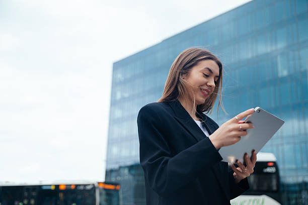istock Professional woman using tablet outdoors in urban setting with modern architecture in background showcasing technology and connectivity concept 2243949167