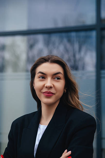 istock Young Woman in a Black Blazer Smiles Confidently While Standing in an Urban Setting During a Sunny Day 2243949230