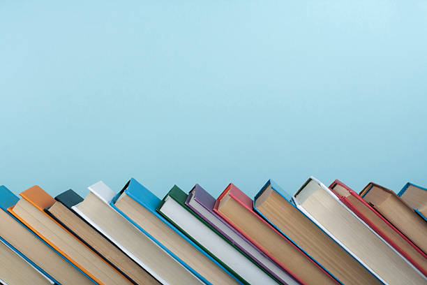 istock Book stacking. Open book, hardback books on wooden table and blue background. Back to school. Copy space for text. 2243950114