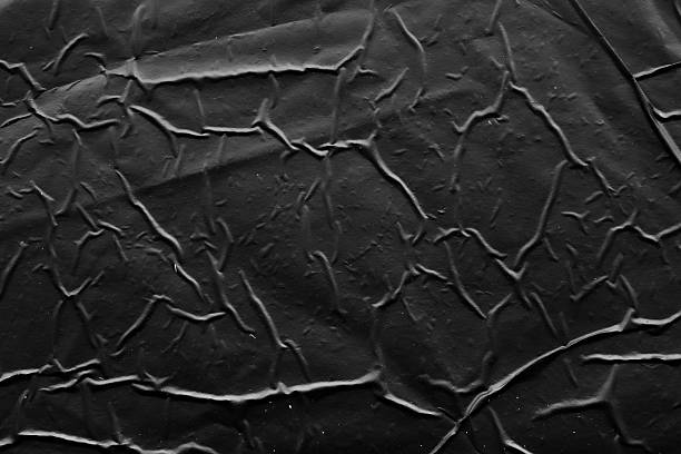 istock black crumpled and creased plastic poster texture background 2243950304