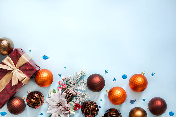 istock Festive Christmas gift box with ornaments and snowy pine decor on blue background 2243956749