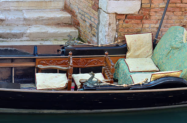Interior of gondola, moored on Venice canal. Tourists from all the world enjoy the historical city of Venezia in Italy, famous UNESCO World Heritage Site