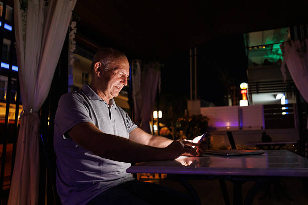 istock Senior Caucasian man reading an ebook using smart phone at home at night 2243958731