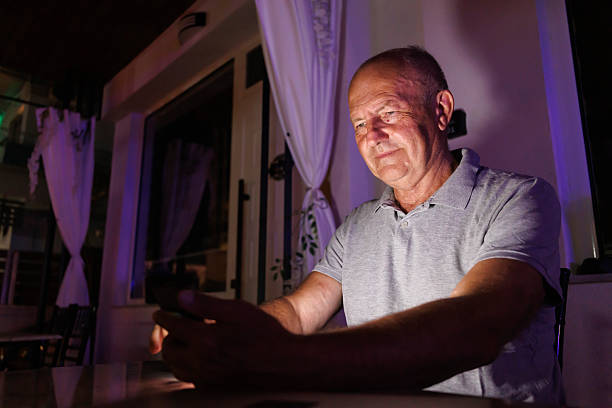 istock Senior Caucasian man chatting online using smart phone at home at night 2243958820