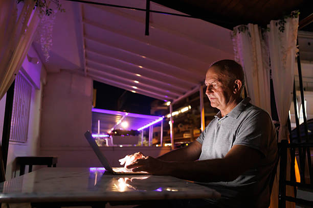 istock Senior Caucasian man having video call using laptop computer while relaxing at home at night 2243959564