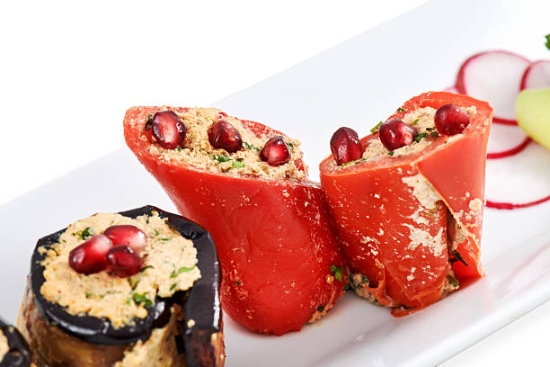 Vibrant stuffed peppers filled with flavorful ingredients, garnished with pomegranate seeds and fresh vegetables, creating an appetizing presentation