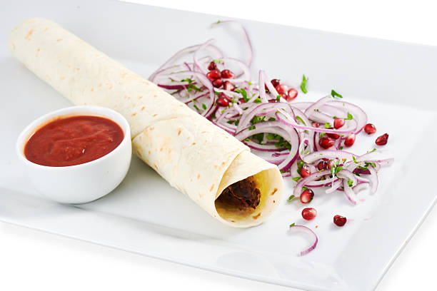Tasty wrap filled with flavorful ingredients, served with fresh onions and pomegranate, creating a vibrant culinary presentation