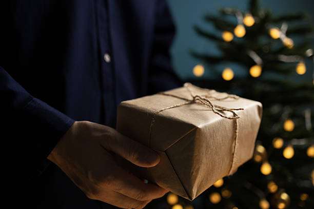 istock Man holding Christmas gift near tree 2243961442