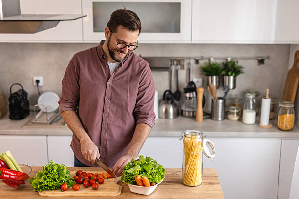 istock Handsome young man man stand at modern kitchen chop vegetables prepare fresh vegetable salad for dinner or lunch, young male cooking at home make breakfast follow healthy diet, vegetarian concept 2243961460
