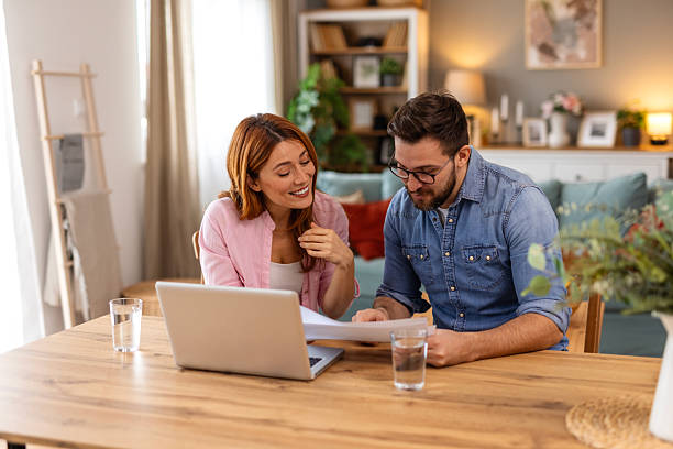 istock Couple is sitting at a table, focused on a laptop screen. They be discussing or working together, highlighting themes of collaboration, technology, and modern lifestyle in a home office setting 2243961527