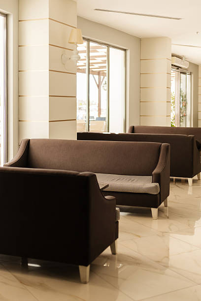 istock Cozy lounge area features several brown sofas arranged in an inviting manner. Natural light floods in through large windows, creating a warm atmosphere perfect for relaxation 2243962131