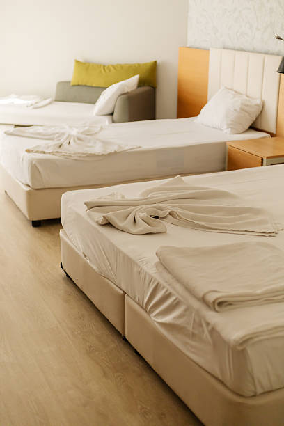 istock A spacious hotel room with two neatly made beds and a comfortable sofa. Soft natural light streams through the window, creating a welcoming atmosphere perfect for relaxation 2243964061