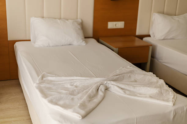 istock A cozy hotel room features two beds with clean, white linens and a simple design. Soft lighting and warm wood tones create a welcoming atmosphere for guests 2243964077