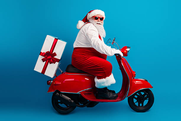 istock Santa on a bright red scooter with a wrapped gift box rides cheerful blue studio to celebrate Christmas Eve and share holiday magic 2243965333