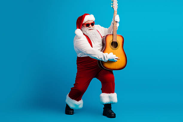 istock Santa Claus plays guitar in a festive studio scene against a bright blue background for holiday music fun and Christmas inspiration 2243965384