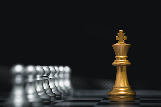 istock Golden chess king piece standing against silver pawns on a chessboard, symbolizing leadership, strategy, decision making, business success, power, dominance, and competitive advantage. 2243966048