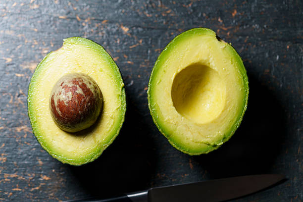 istock Fresh avocado halves on dark stone background 2243966621