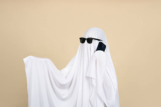 istock Creepy ghost. Person covered with white sheet on beige background 2243966956