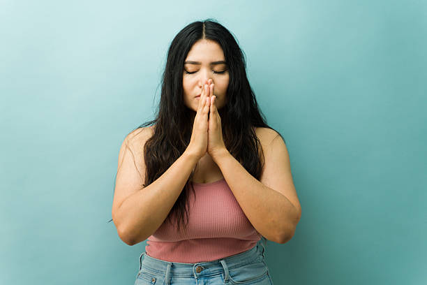 istock Woman praying with hands clasped meditating 2243967363