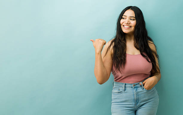 istock Young woman pointing finger presenting copy space 2243968120